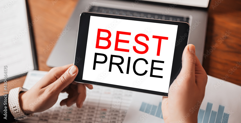 Man hands holding tablet with text BEST PRICE at workplace. Businessman working at desk with documents Man hands holding tablet with text BEST PRICE at workplace. Businessman working at desk with documents