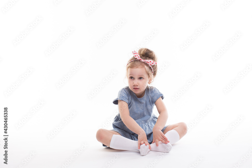 Childhood, emotions concept, little cute girl in a blue dress posing in the studio on a white Childhood, emotions concept, little cute girl in a blue dress posing in the studio on a white