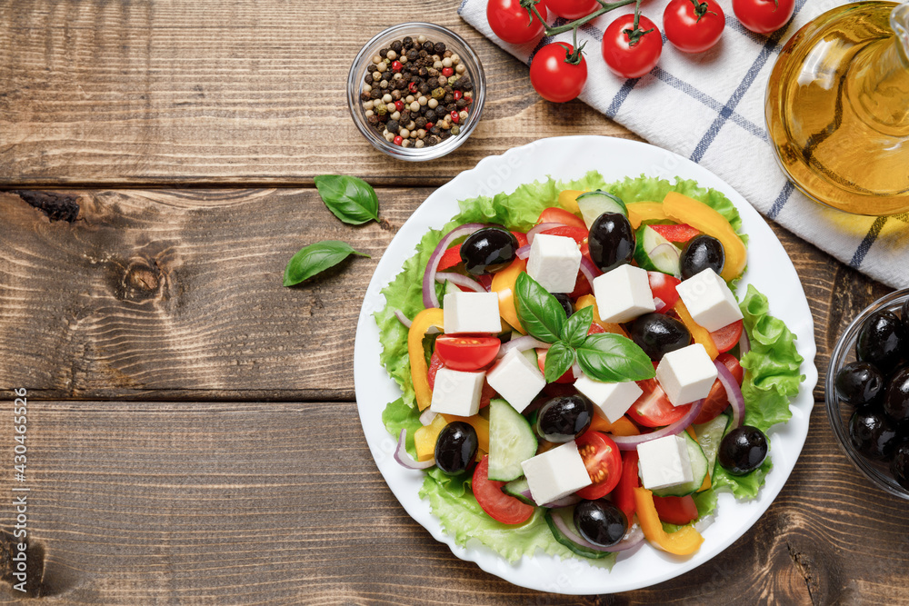 Greek salad with cheese and fresh vegetables on wooden background. Flat lay, top view, copy space