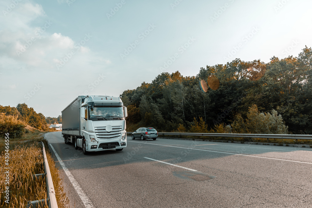 Arriving white truck on the road in a rural landscape at sunset Arriving white truck on the road in a rural landscape at sunset