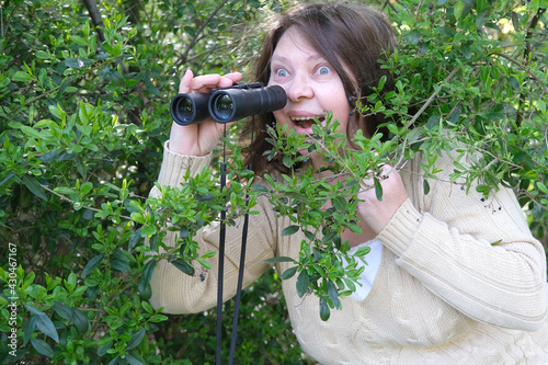 Obraz na plátně sly curious European adult woman holding black field binoculars with zoom in her
