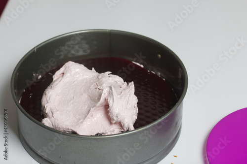 A woman prepares a marshmallow cake. Places a layer of jelly and marshmallows on the biscuit. Works with a mask and gloves.