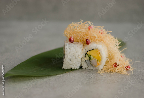 Sushi Uramak na zielonym liściu pokryte ciastem filo, posypane żurawiną