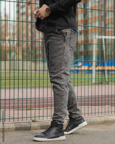 Young fashion man's legs with black sneakers. Black shoes