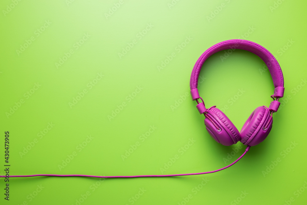 Pink wired stereo headphones on green background. Pink wired stereo headphones on green background.