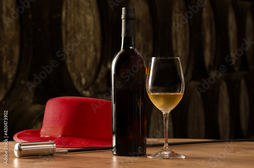 Bottle and glass of fino white sherry wine in winery with typical Jerez with Venetian and red hat photo