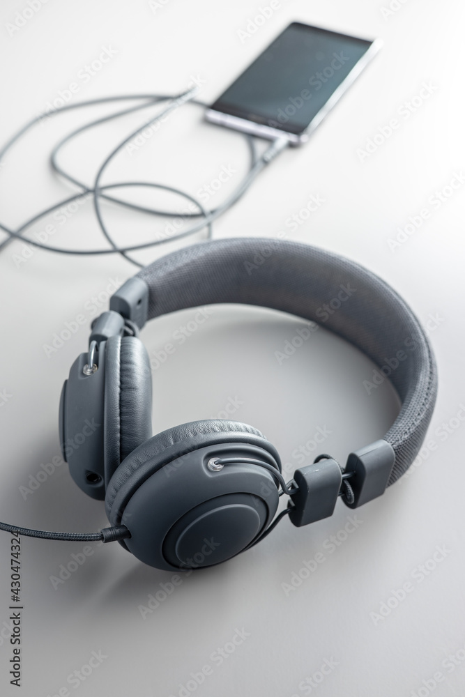 Wired stereo headphones connected to the smartphone on a gray background. Wired stereo headphones connected to the smartphone on a gray background.