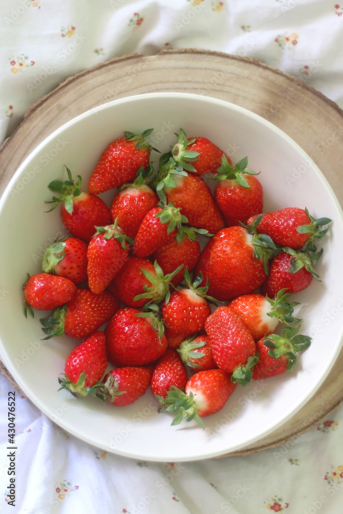 Bowl of fresh strawberries and wooden tray on a bed. Flat lay. Bowl of fresh strawberries and wooden tray on a bed. Flat lay.