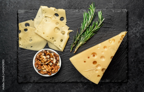 Maasdam cheese with walnut and rosemary on stone background photo