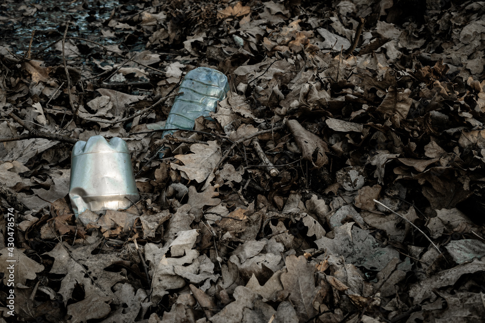 Obraz premium Environmental pollution. Waste rubbish in forest. Plastic garbage trash in woodland. Ecological problem with Empty used dirty plastic bottles.
