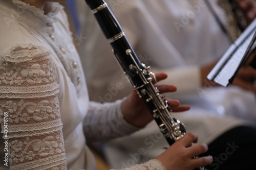 Close-up of a girl musician playing the clarinet in an orchestra in a white blouse with an openwork sleeve.Selective focus. Art Photography