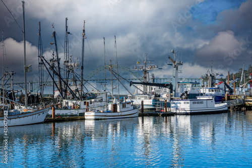 Newport, Oregon - 3-9-2021: Commercial fishing boats in harbor with Yaquina Bay Bridge and stormclouds in background