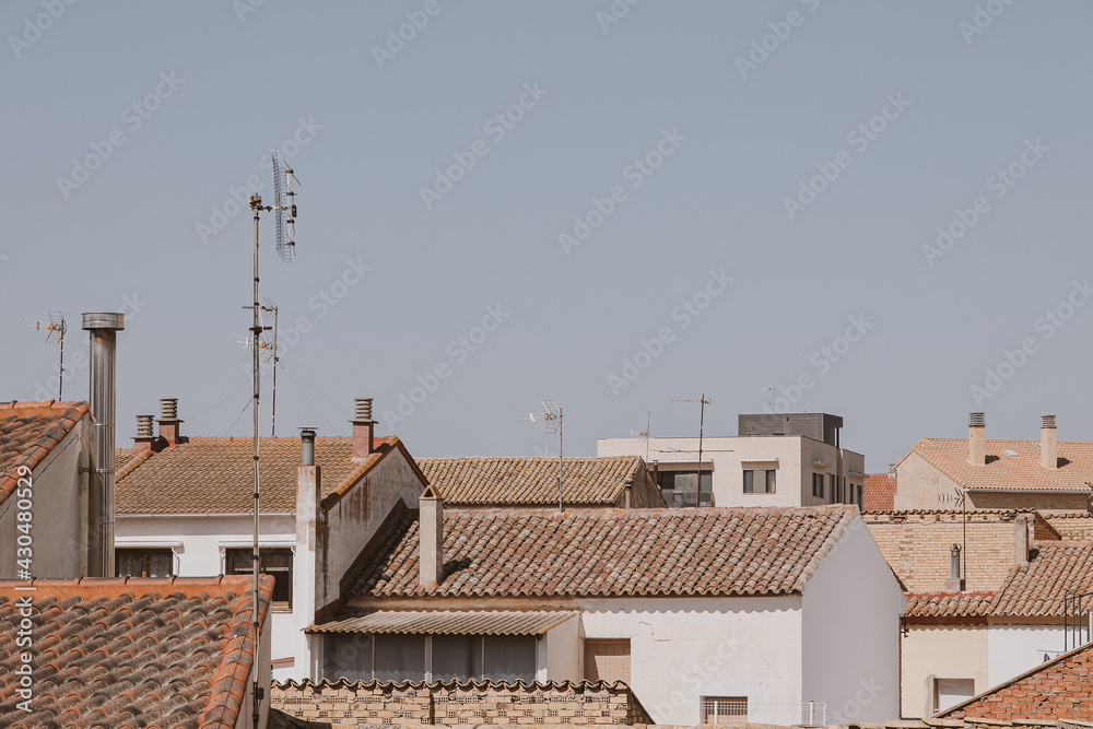 background with spanish tiled roofs of houses against a cloudless blue sky