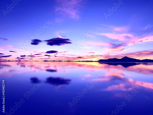 Sunset over lake. Wonderful sunset in mountains. Surreal natural landscape at salt flat Salar de Uyuni. Bright colors of desert. Incredible sky clouds reflection in calm water. Magical alien nature.