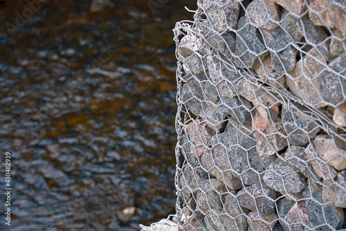 Gabion wall constructed using steel wire mesh basket. Stone walls, gabion revetment - protection from backshore erosion. Gabion and rock armour - coastal and waterways protection. photo