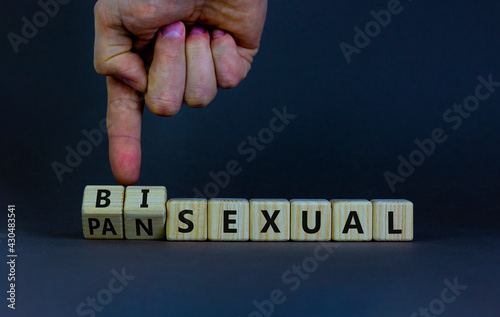 Pansexual or bisexual symbol. Doctor turns wooden cubes and changes the word 'bisexual' to 'pansexual'. Beautiful grey background, copy space. Social, pansexual or bisexual concept.