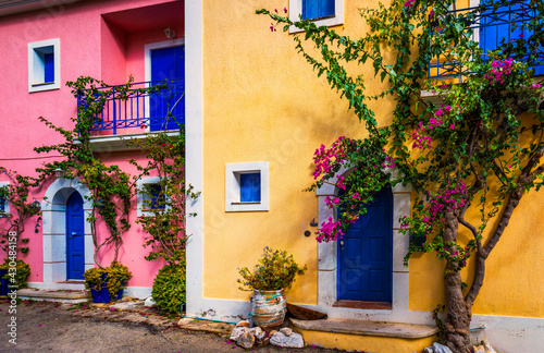 Traditional street with greek houses with flowers in Assos  Kefalonia island. Traditional colorful greek houses in Assos village. Blooming fuchsia plant flowers. Kefalonia island  Greece