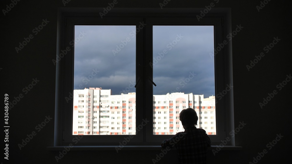 A lonely child looks out the window of his house in an apartment. A lonely child looks out the window of his house in an apartment.