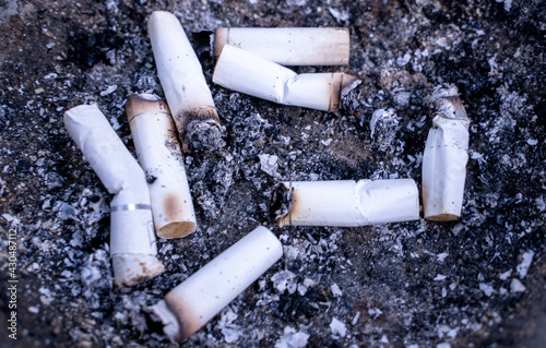 Lots of smoked cigarette buds in a large ash tray on a public area photo