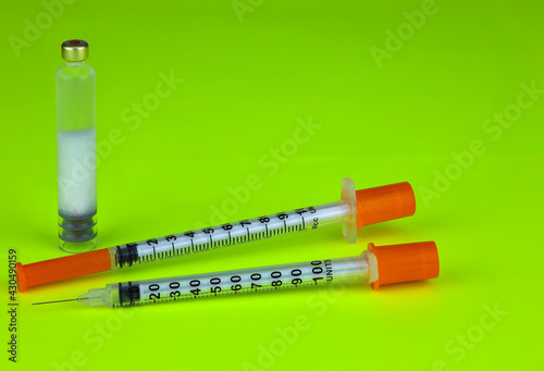 Insulin syringes and ampoule - insulin cartridge on a green background. A concept for diabetes compensation.