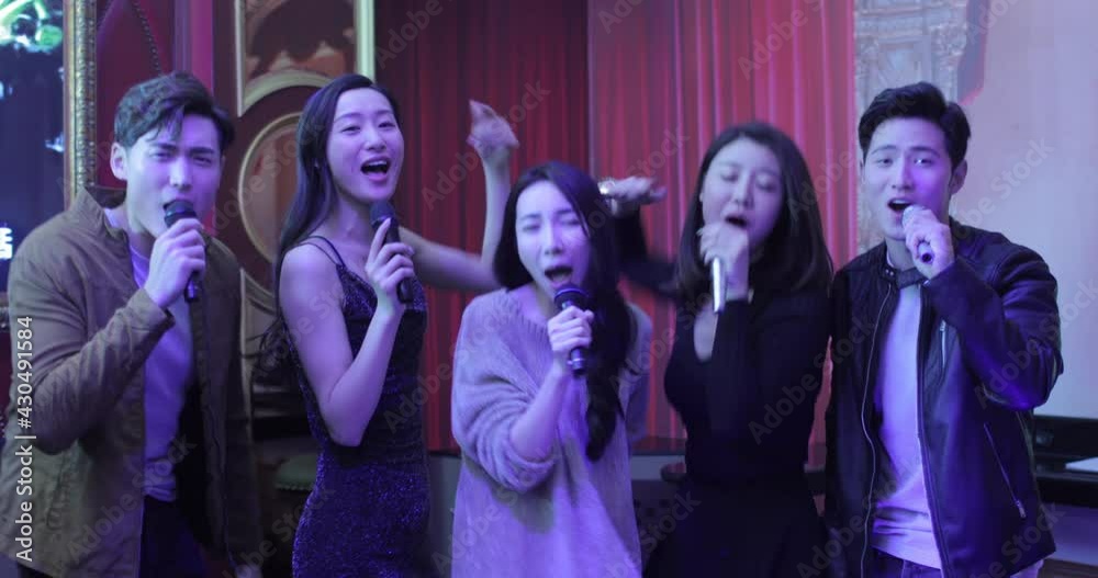 Happy young friends singing karaoke in nightclub,4K