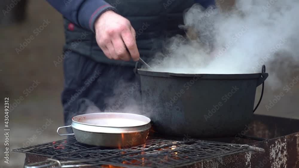 Hot food is cooked over a fire in the forest. Soup in a cauldron Hot food is cooked over a fire in the forest. Soup in a cauldron