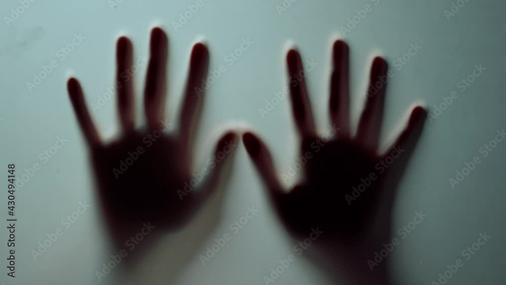 Macro two female hands pressing against glass wall indoors.Blurred hands shadow. Macro two female hands pressing against glass wall indoors.Blurred hands shadow.