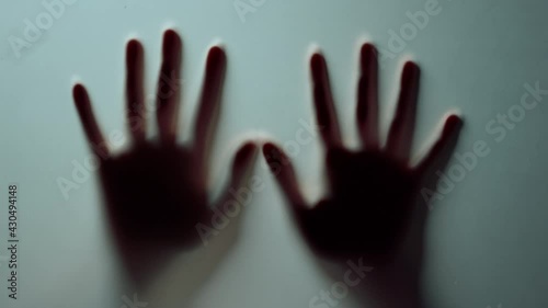 Macro two female hands pressing against glass wall indoors.Blurred hands shadow.