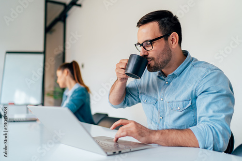 Businessman drinking coffee while using laptop