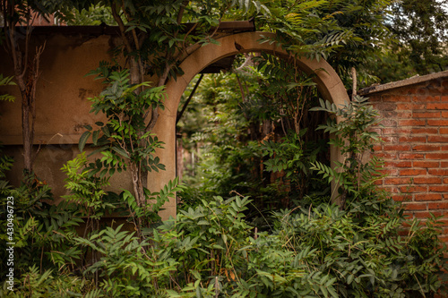 Stone arch in an old abandoned park with lots of greenery on a summer day