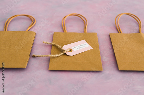 women-owned business tag on shopping bag surrounded by competitors' bags, supporting equality