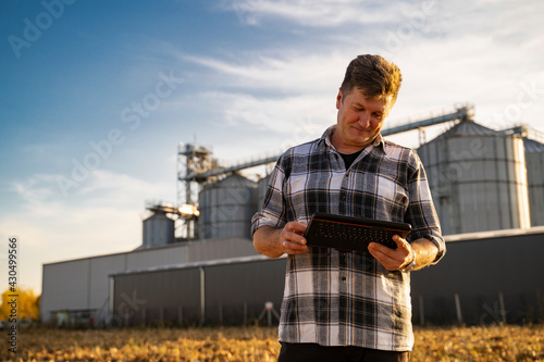 Closeup of man looking at tablet satisfied. Grain silos in background 
