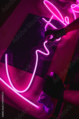 Cropped view of craftsman cleaning neon signboard in workshop 