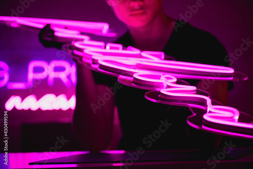 Cropped view of designer holding trendy neon signboard on dark background 