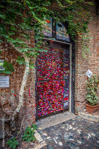 Verona, Italy, 07.04.2019: view of the door with love notes and padlocks located at Juliet's house yard in historical part of the city of Verona