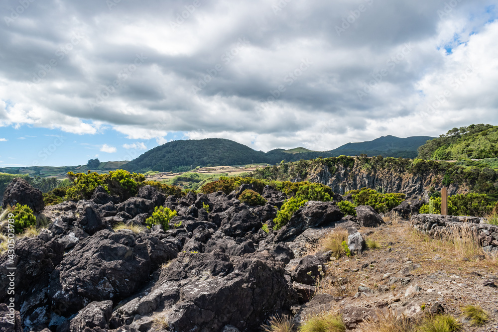 Volcanic stones and shrubs with mountains in the background at the Natural Reserve of Alagoa da Fajãzinha, Terceira - Azores PORTUGAL