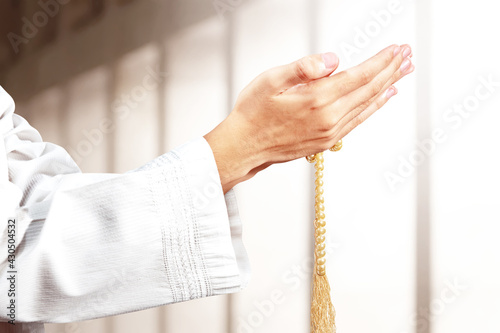 Muslim man praying with prayer beads on his hands