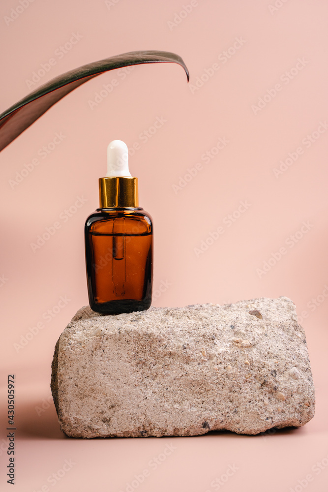 The bottle of Essence is on the pedistal. Lotion on a Beige background. Cosmetics for skin health. Aromo Oil. Serums with vitamin C. Unisex cosmetics. Mockup. 