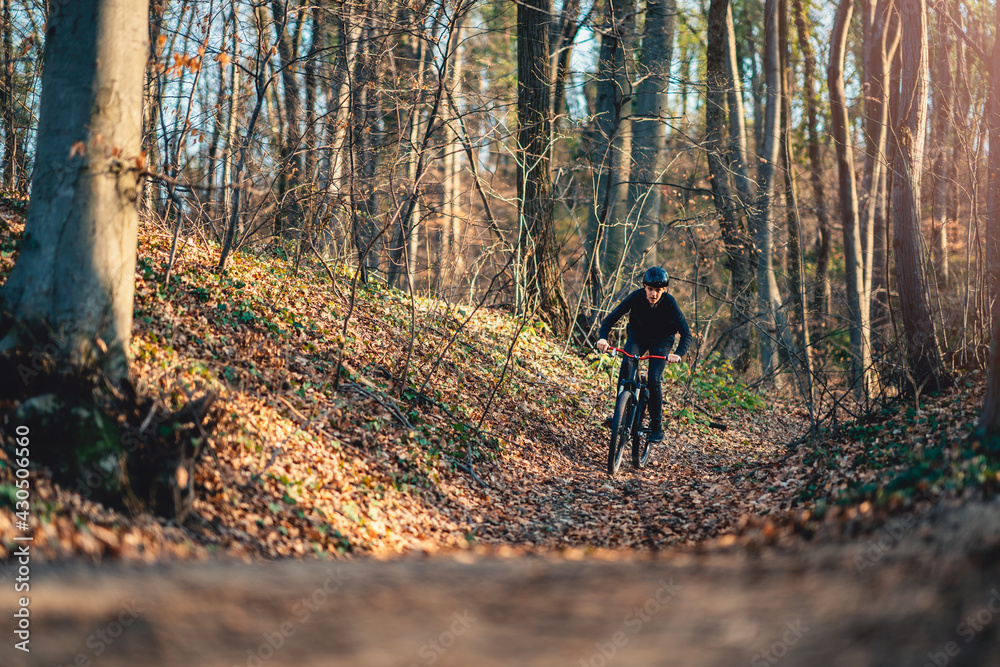 Teenage boy riding mountain bike through forest