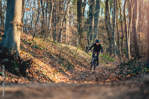 Teenage boy riding mountain bike through forest
