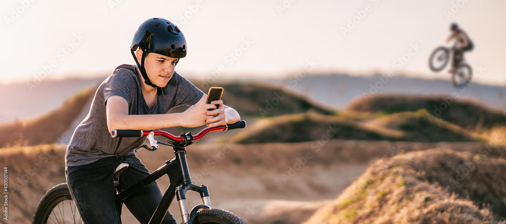 Teenager with a bicycle helmet,using a mobile phone,messaging