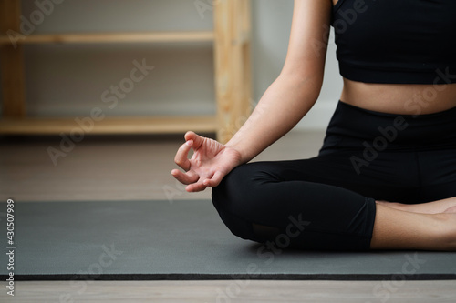 Close up view of young women practicing yoga the easy sitting pose (sukhasana) in the living room, work out at home, meditating.