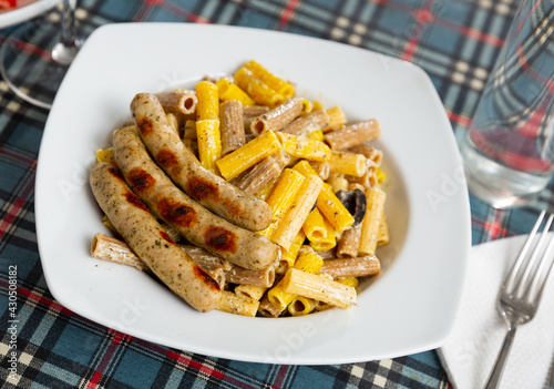 Delicious Rigatoni pasta with fried sausages in cream sauce and olives