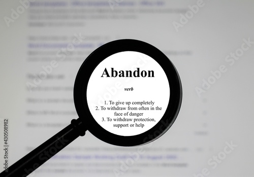 Selective focus on word abandon, word in a dictionary. Close up of an English dictionary page with the word abandon