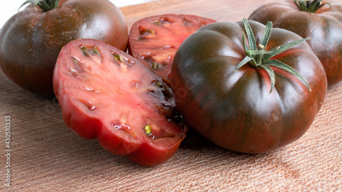 Deliciously vibrant amore tomato on a wooden cutting board. Graded in dark green and dark red colors, this unique tomato packs a sweet punch. Vegetable and dieting food concept photo. photo