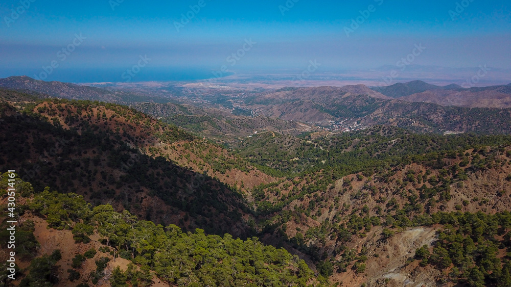 Aerial view of a gorge at the foothills of the Troodos Mountains with green pine trees and the Mediterranean Sea on the horizon, Cyprus photo by drone