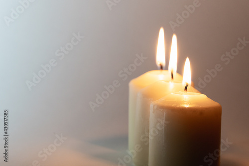 Three lighted candles on a white background