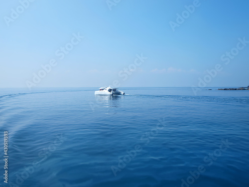 Beautiful view of sea and yacht. Scene of motor yacht in the sea. Rocks on a distance. Horizon line. Ripple and wake trace on the surface of water. Pleasure tourist boat, sea travel, touristic service © Oxana