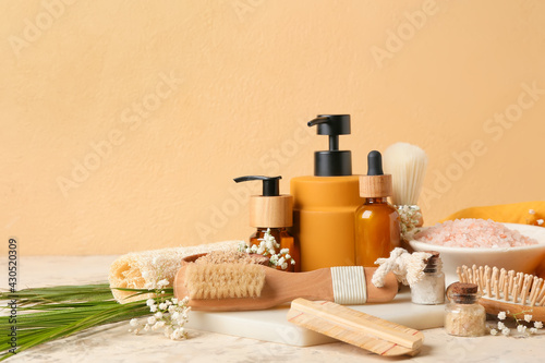 Composition with massage brushes, bath supplies and flowers on color background