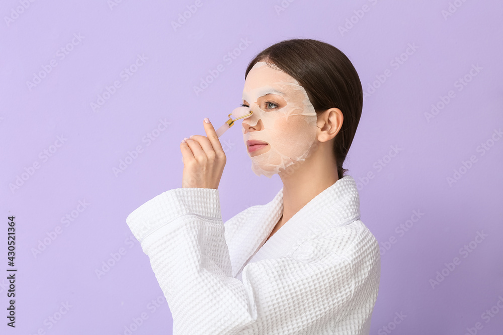 Beautiful young woman with sheet facial mask and massage tool on color background Beautiful young woman with sheet facial mask and massage tool on color background